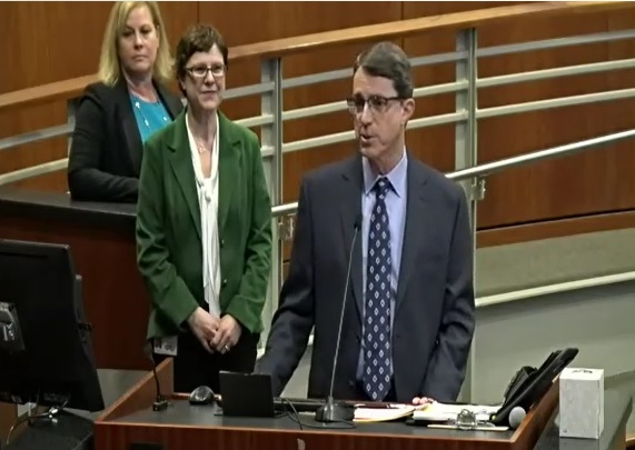 Two women and Dr. Paul Simon speaking at the podeum at the Board of Supervisor's meeting