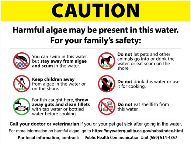 Sign with yellow top with "Caution: Harmful algae may be present in this water and safety tips